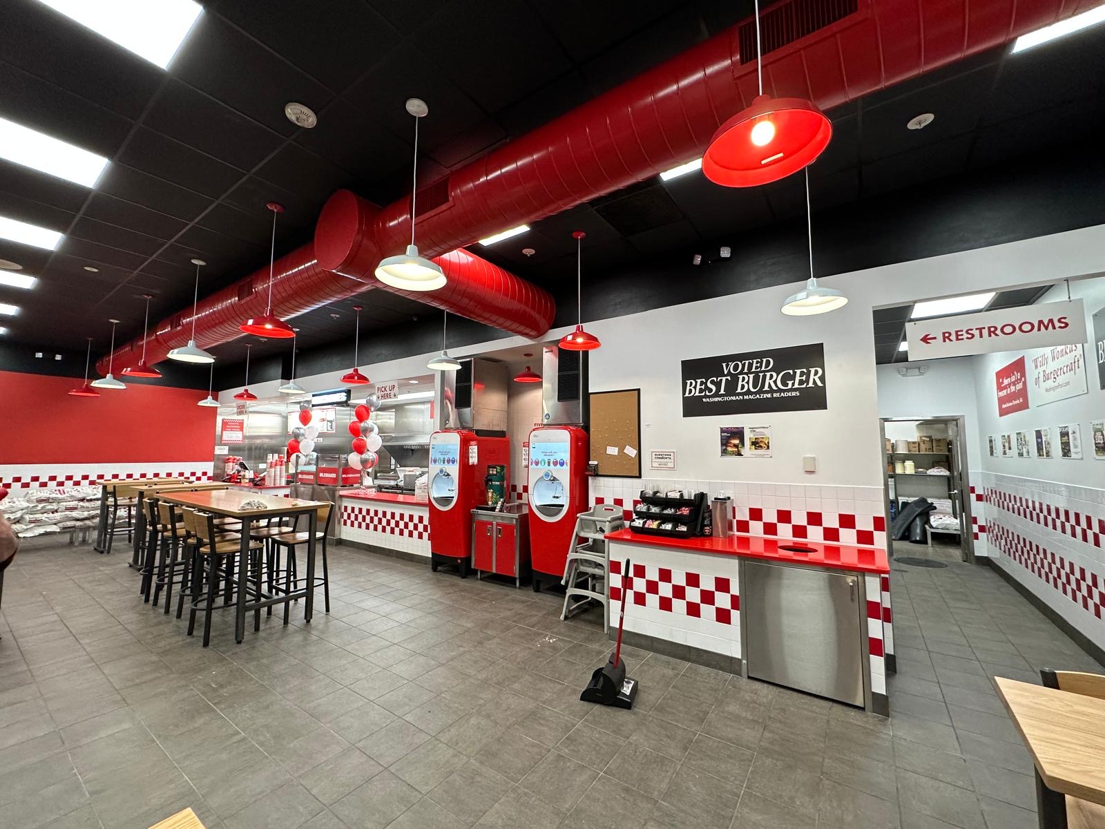 Finished Five Guys dining area with high-top tables and red accent lighting