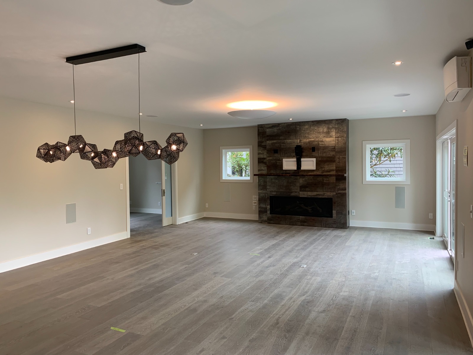 Renovated great room with tiled fireplace wall and geometric chandelier