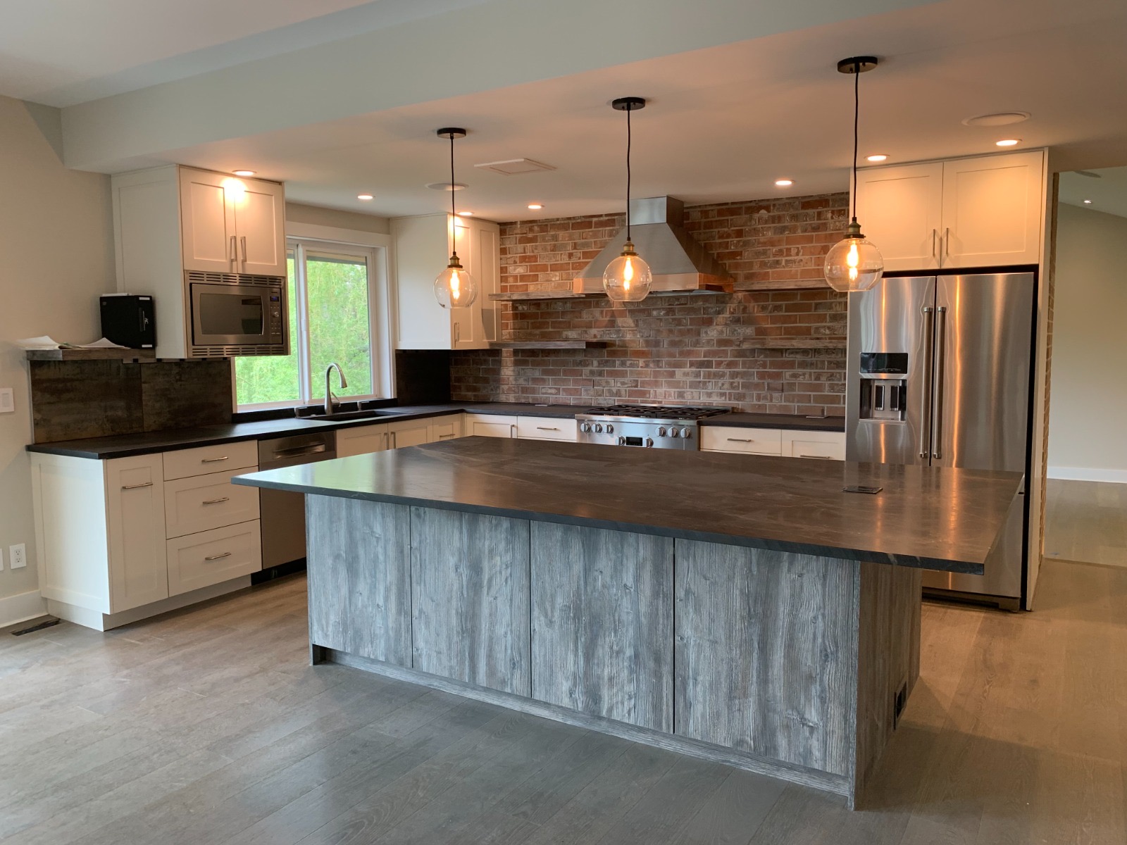 Remodeled kitchen with brick backsplash, quartz island, and stainless appliances