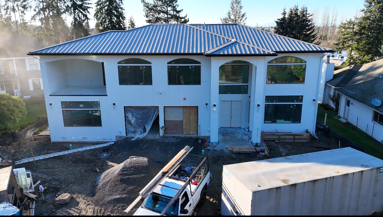 Two-story custom home under construction with standing-seam metal roof