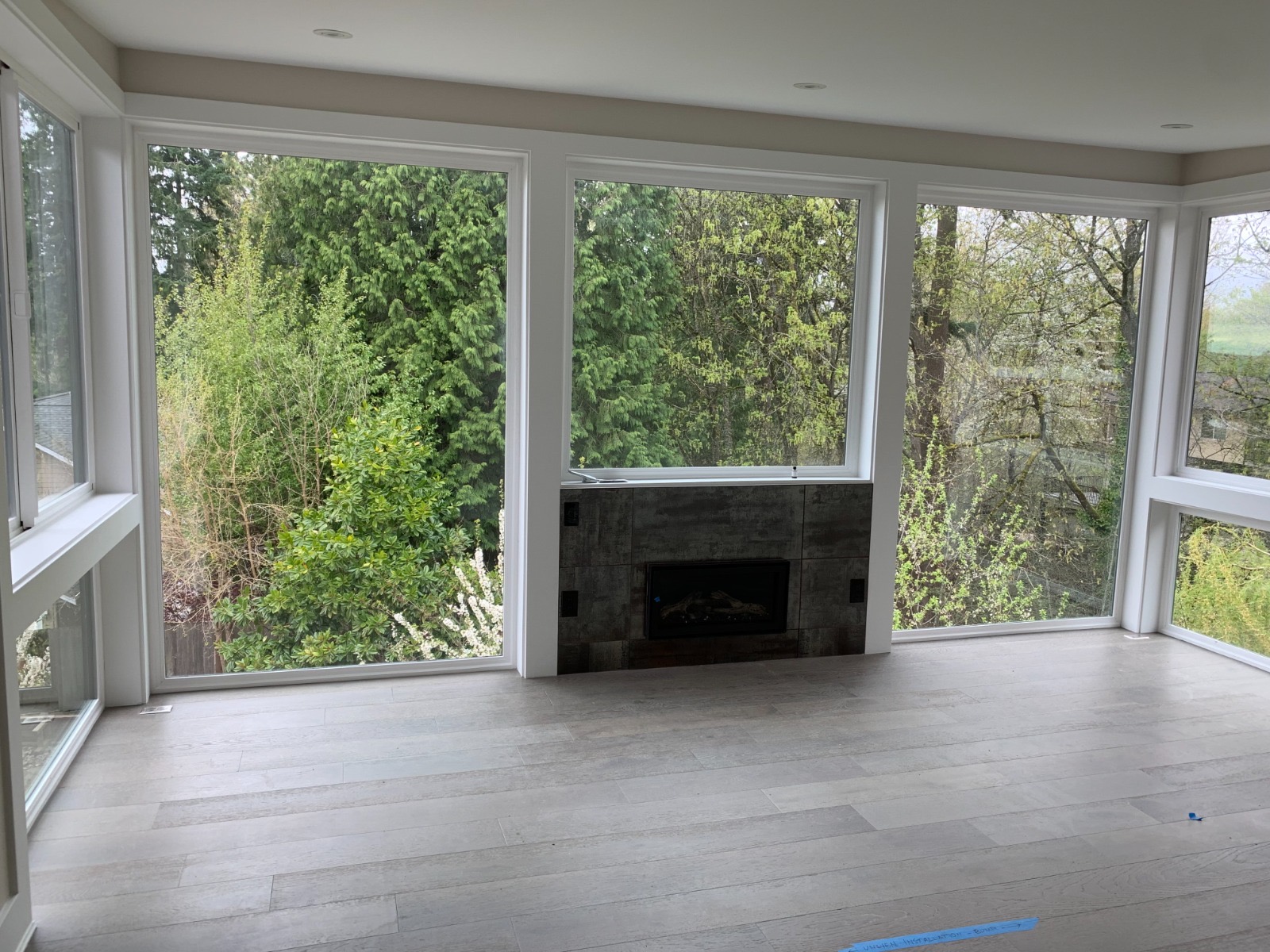 Finished sunroom addition with wall-to-wall windows and tiled fireplace